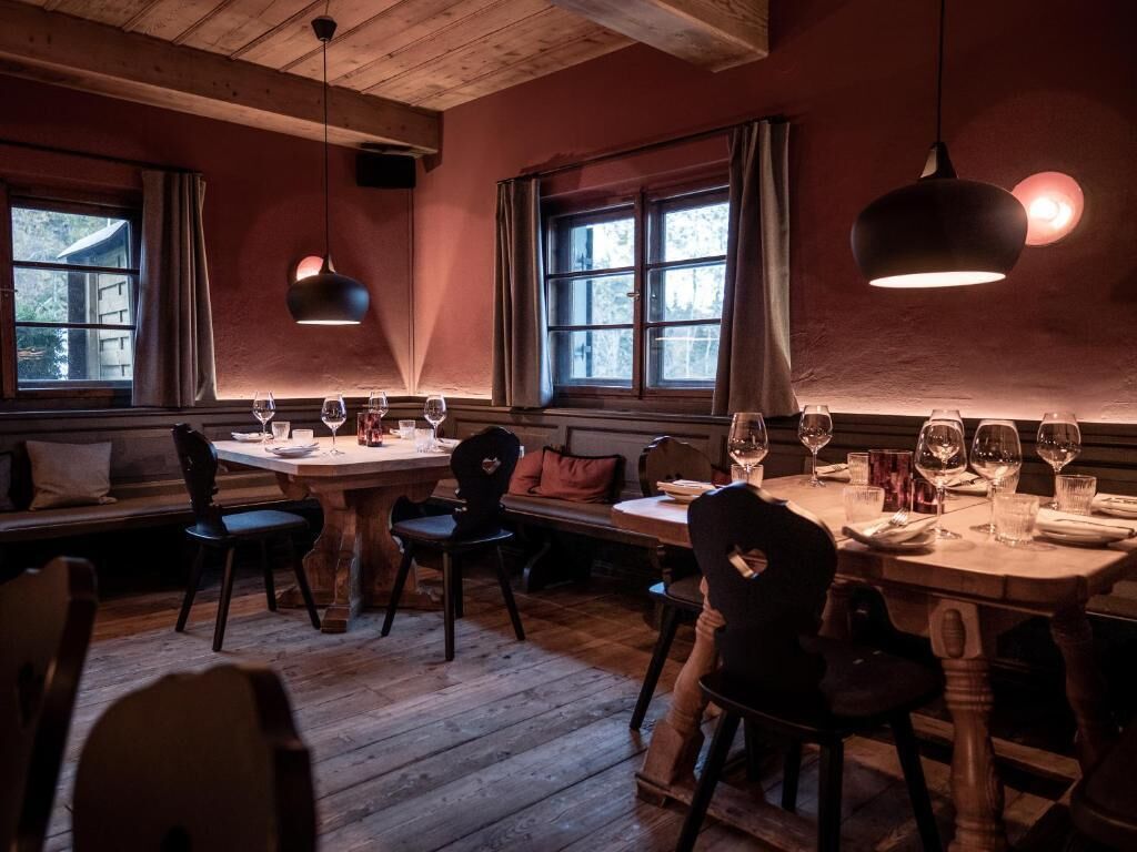 Ein gemütlicher Essbereich mit Holzmöbeln, einem Tisch für zwei Personen und Blick ins Freie durch ein Fenster.
