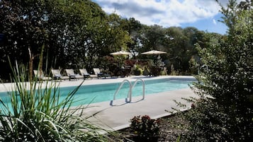 Una piscina al aire libre de temporada, sombrillas