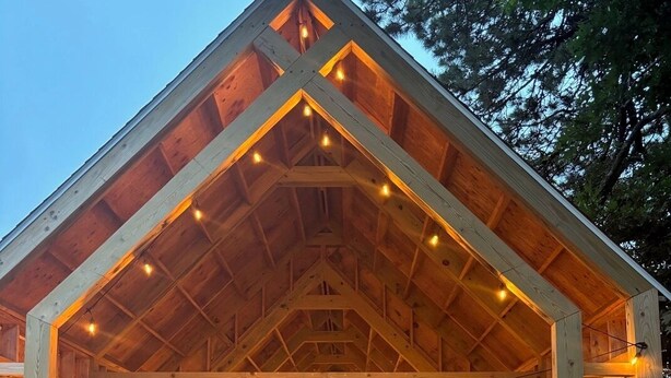 A wooden building with a pitched roof, string lights, and potted plants.