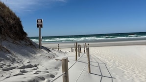 A sandy beach with a sign that reads "KEEP OFF DUNES" and wooden posts.