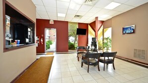 A hotel lobby with a reception desk, a coffee machine, a fire extinguisher, a TV, and a seating area with chairs and a table. - Americas Best Value Inn Phillipsburg (Phillipsburg)
