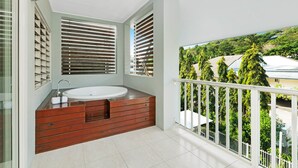 A balcony with a view of a residential area, a wooden bathtub, and a window with blinds. - Mantra Aqueous on Port (Port Douglas)