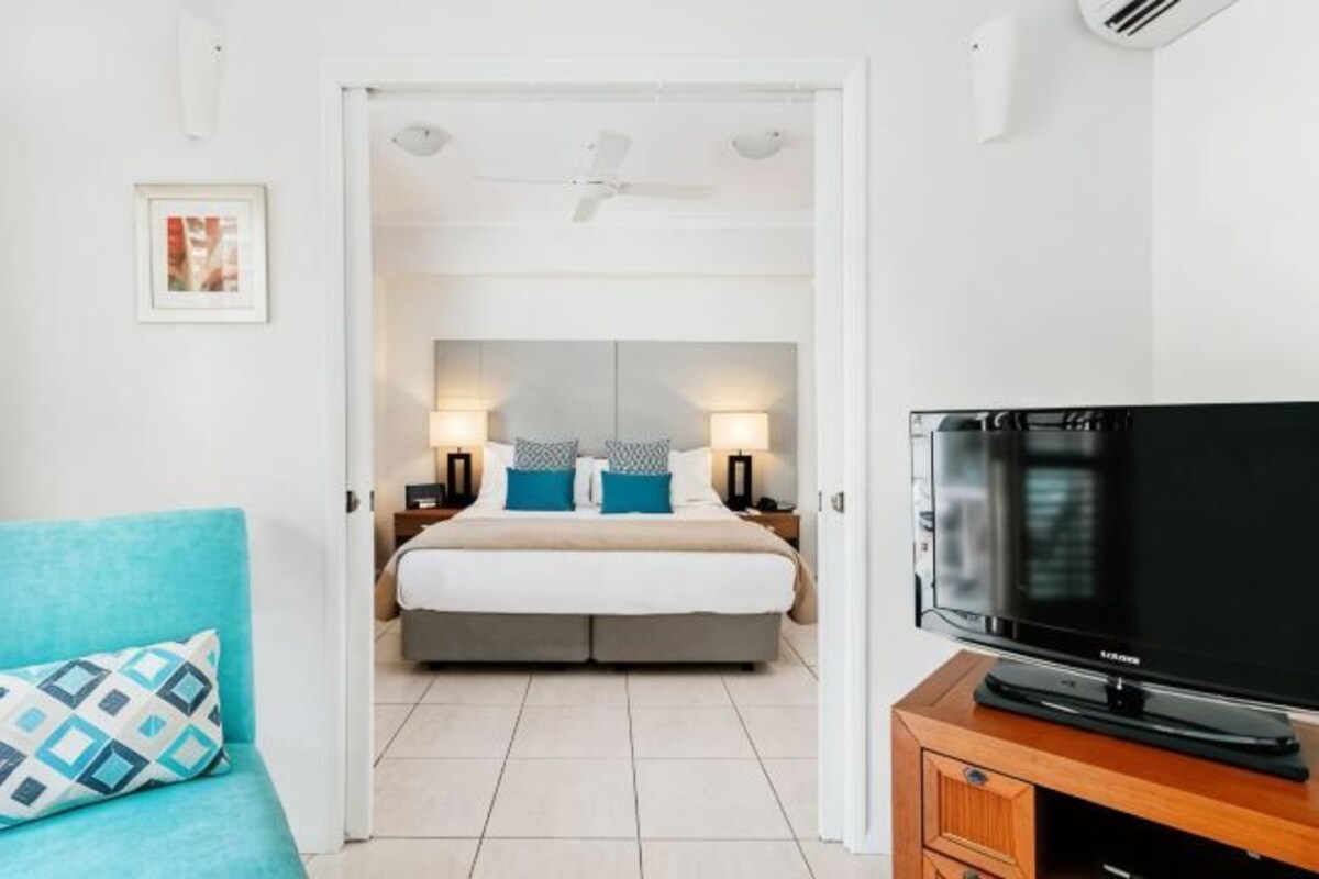 Ett hotellrum med en säng, en tv, en soffa och en takfläkt.