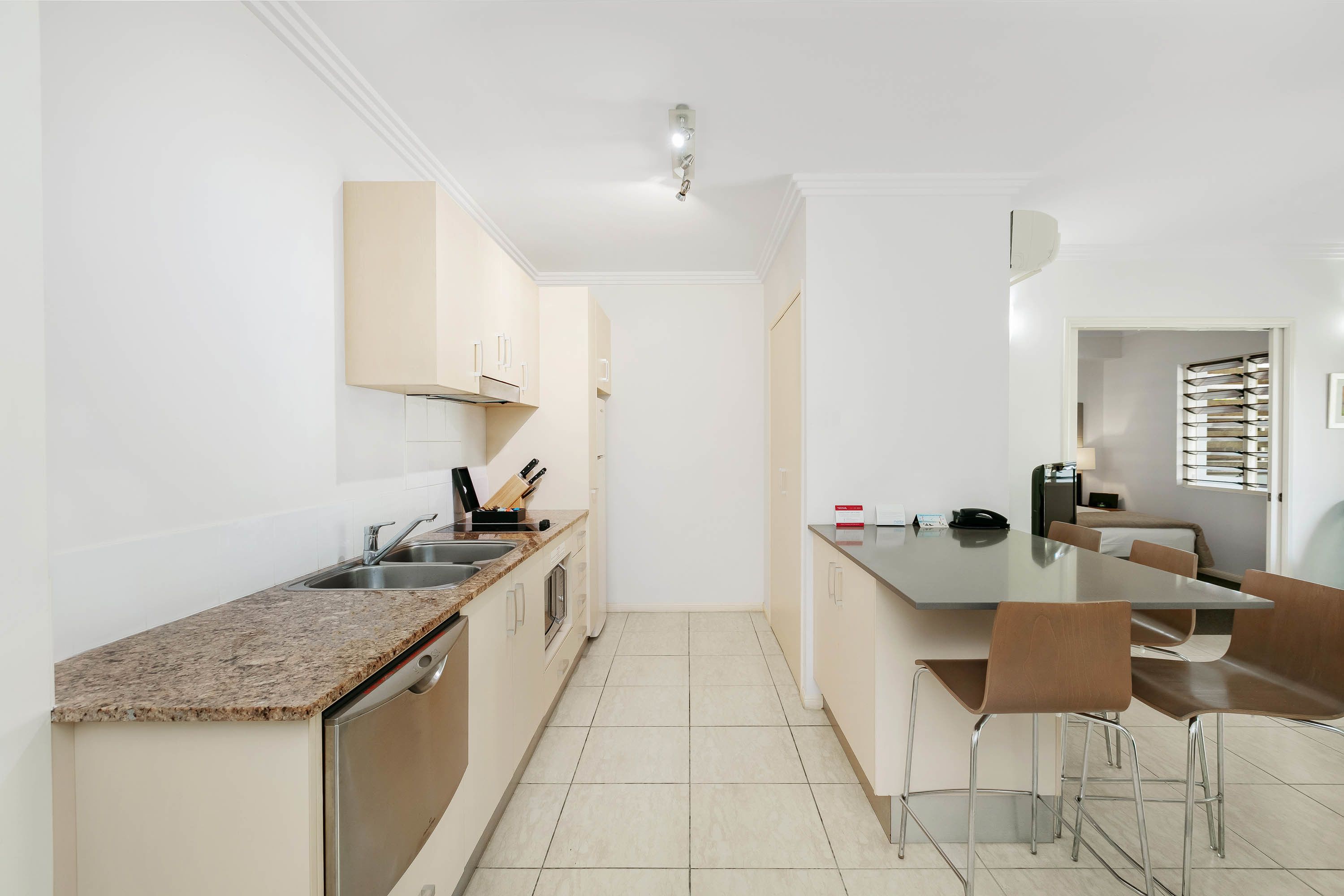 Una cocina moderna con encimera de granito, electrodomésticos de acero inoxidable y una zona de comedor con mesa y sillas.