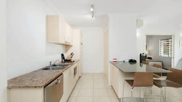 Una cocina moderna con encimera de granito, electrodomésticos de acero inoxidable y una zona de comedor con mesa y sillas.