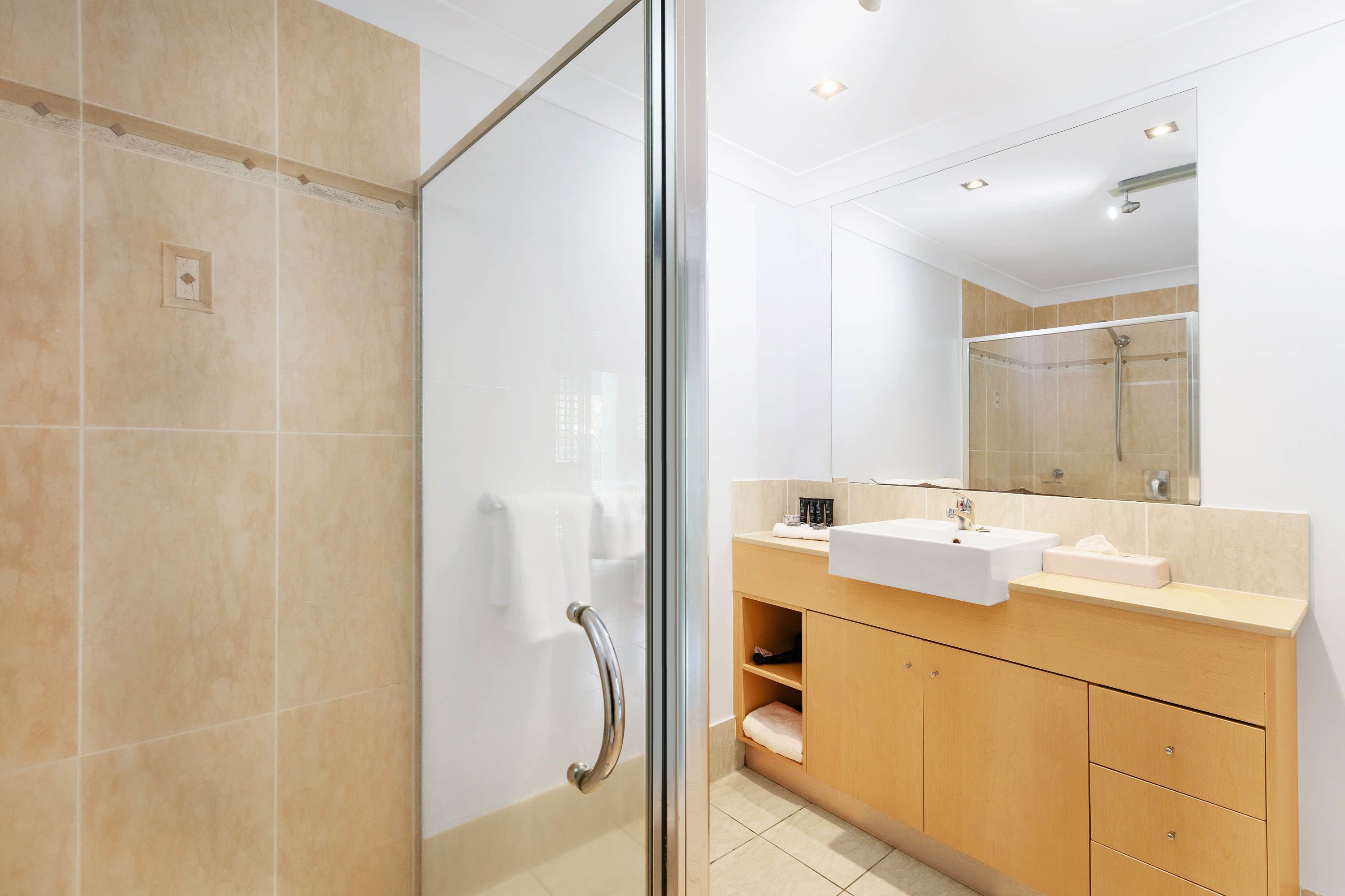 Un bagno moderno con box doccia in vetro, lavandino e mobile contenitore.