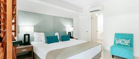 Una habitación de hotel con una cama, mesitas de noche, una silla y un ventilador de techo.