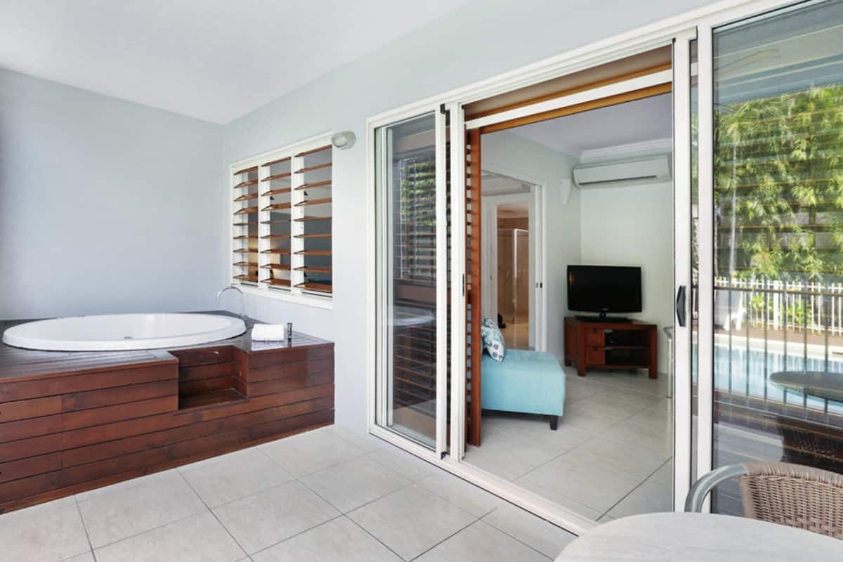 A bathroom with a large sink, wooden vanity, and a shower area.