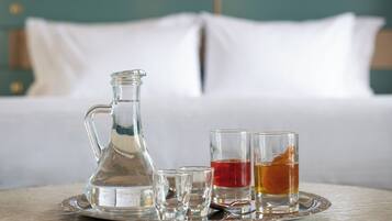 Un plateau avec un pichet en verre, deux verres à shooter et une tasse de thé, posés sur une table dans une chambre d’hôtel.