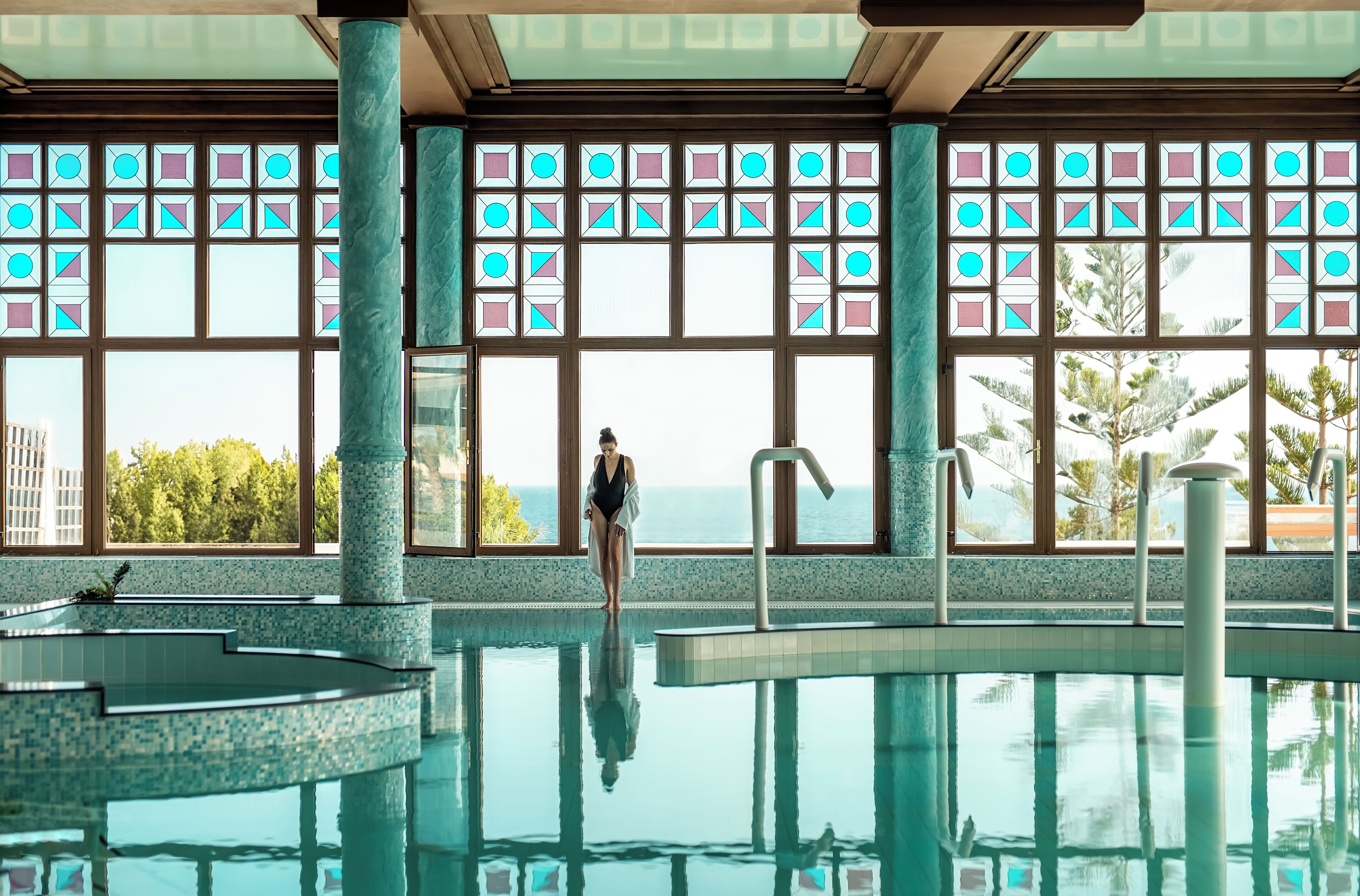 A large indoor swimming pool with clear views of the ocean through large windows.