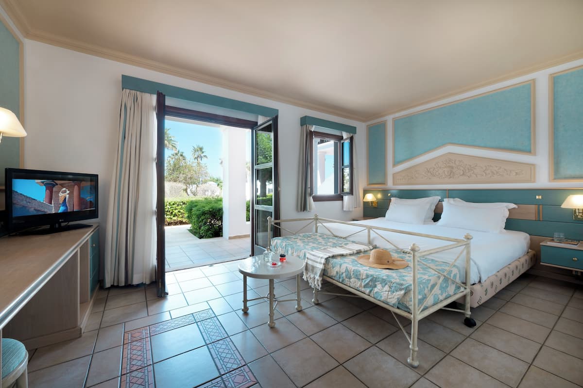 Une chambre d’hôtel avec un lit, un bureau avec une télévision, une petite table et une vue sur l’extérieur.