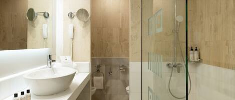 A modern bathroom with a large white sink, a glass-enclosed shower, and a mirror above the sink.