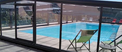 Piscine intérieure, piscine extérieure en saison, chaises longues