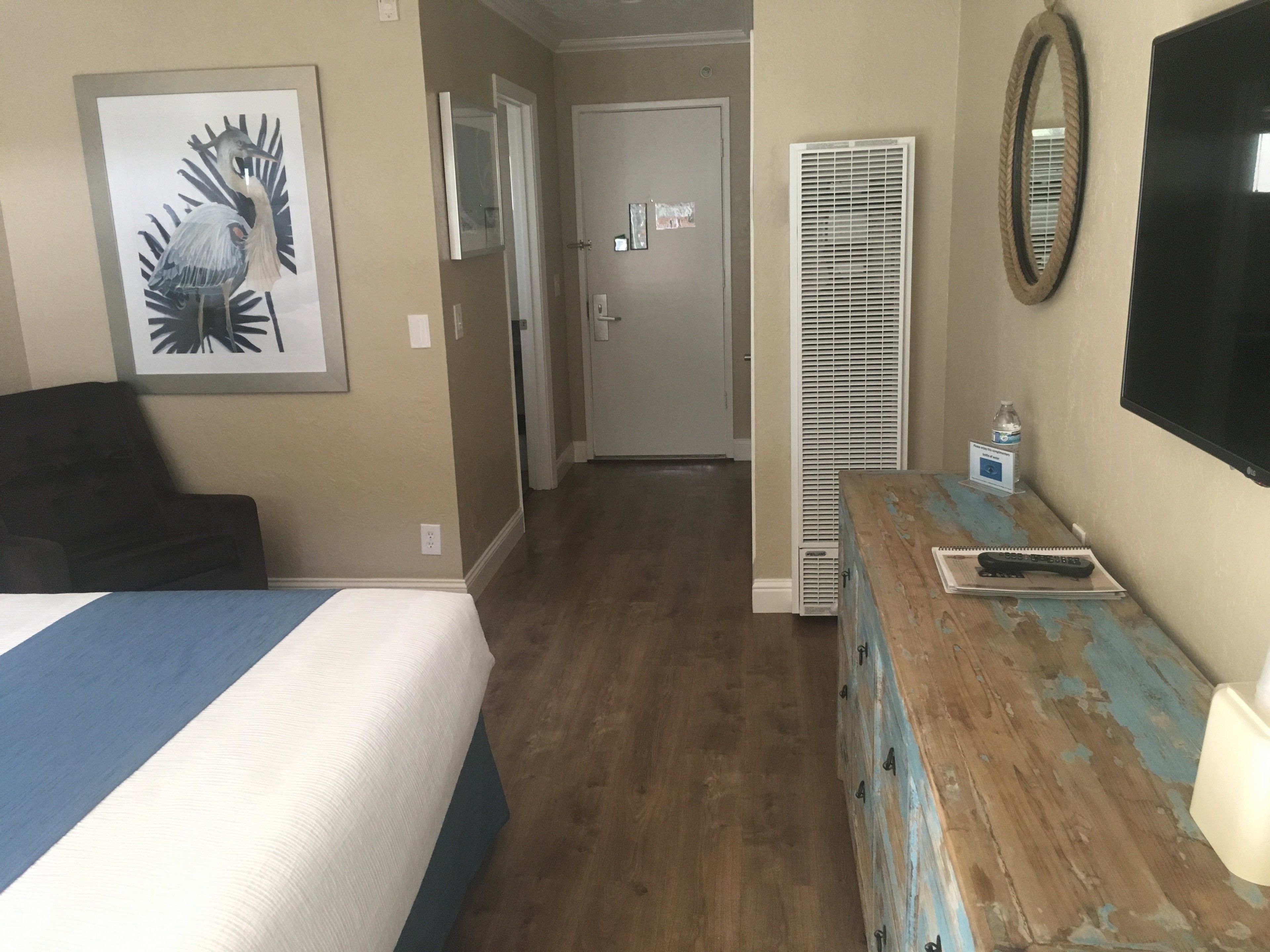 Habitación de hotel con una cama, cómoda, espejo y un cuadro en la pared.