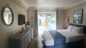 Habitación de hotel con cama, cómoda, televisor, cafetera y vistas al exterior.