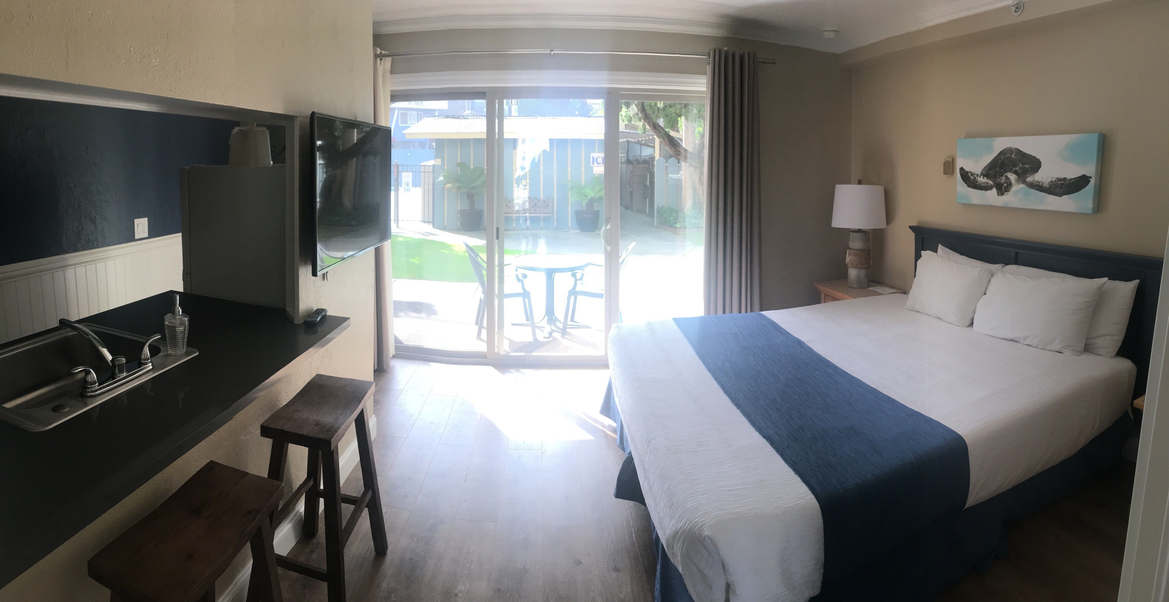 Ein Hotelzimmer mit einem Bett, einem Schreibtisch mit Waschbecken, einem Fernseher und Blick ins Freie.