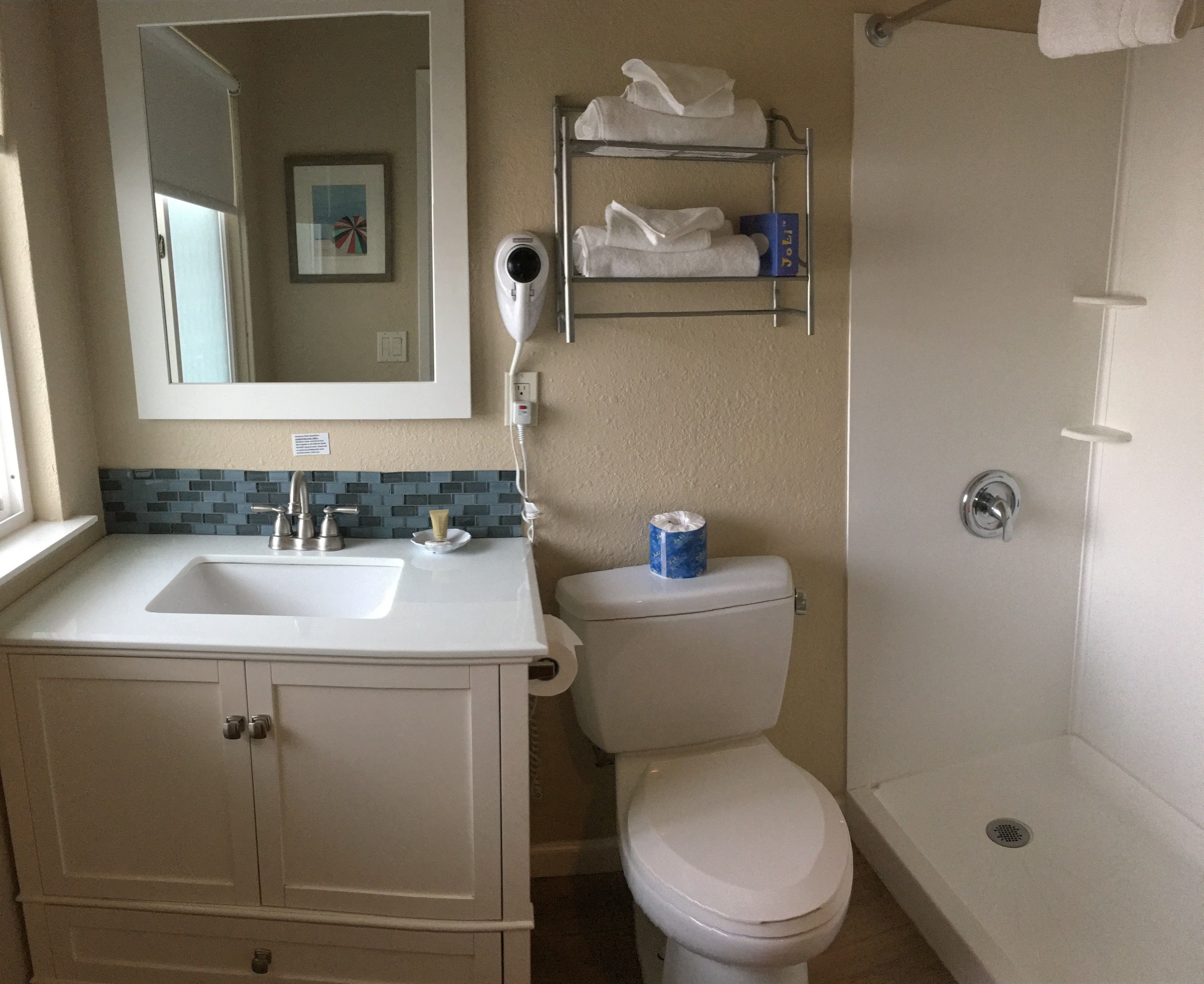 Un baño con lavamanos, espejo, inodoro y ducha.