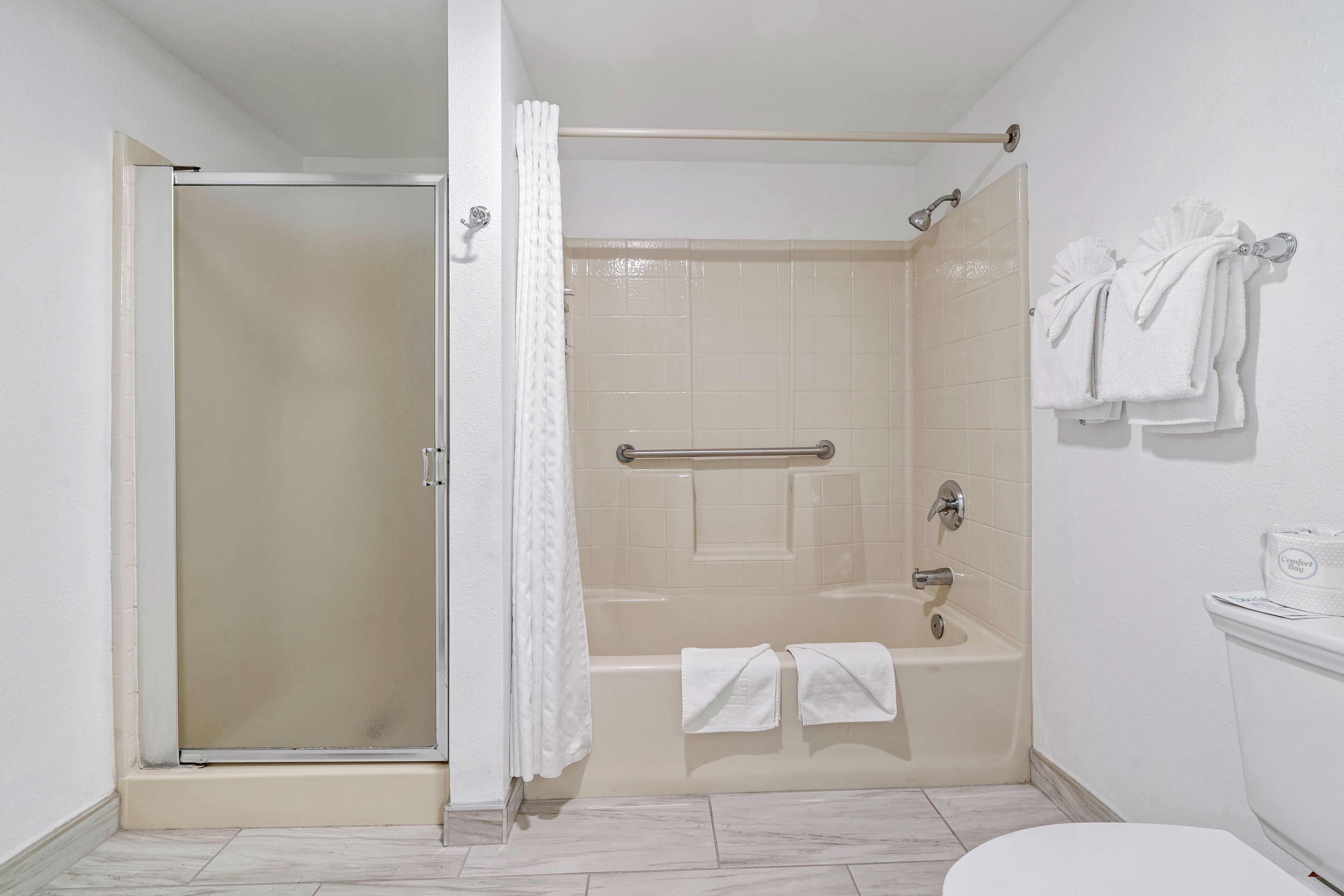 A bathroom with a glass shower enclosure, a bathtub, and a toilet.