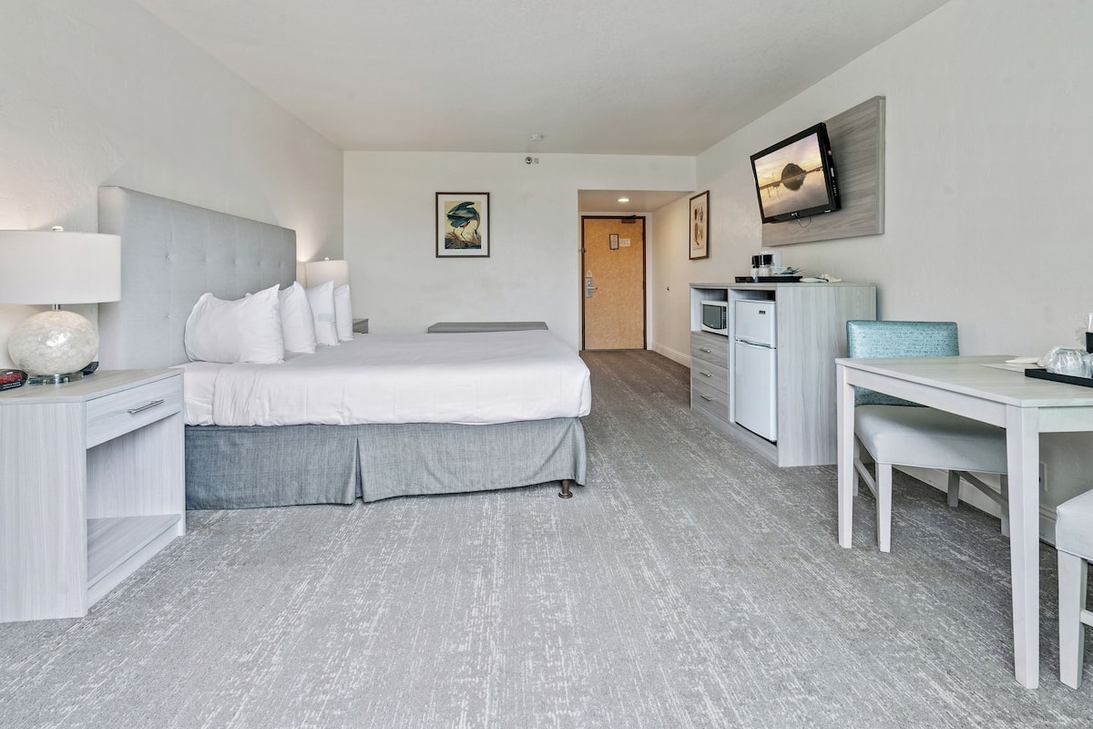 Een moderne hotelkamer met een groot bed, een bureau en een televisie.