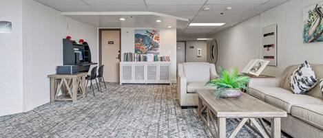 A modern office space with a sofa, a coffee table, a bookshelf, and a desk with a computer.
