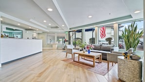A spacious lobby with a reception desk, seating area, and large windows. - La Serena Inn (Morro Bay)
