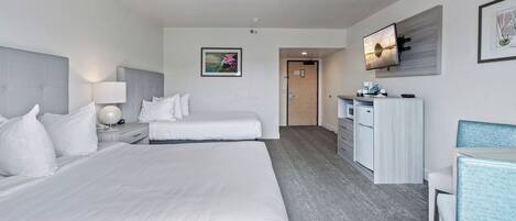 Ett hotellrum med två sängar, ett skrivbord, en stol, en tv och en tavla på väggen.