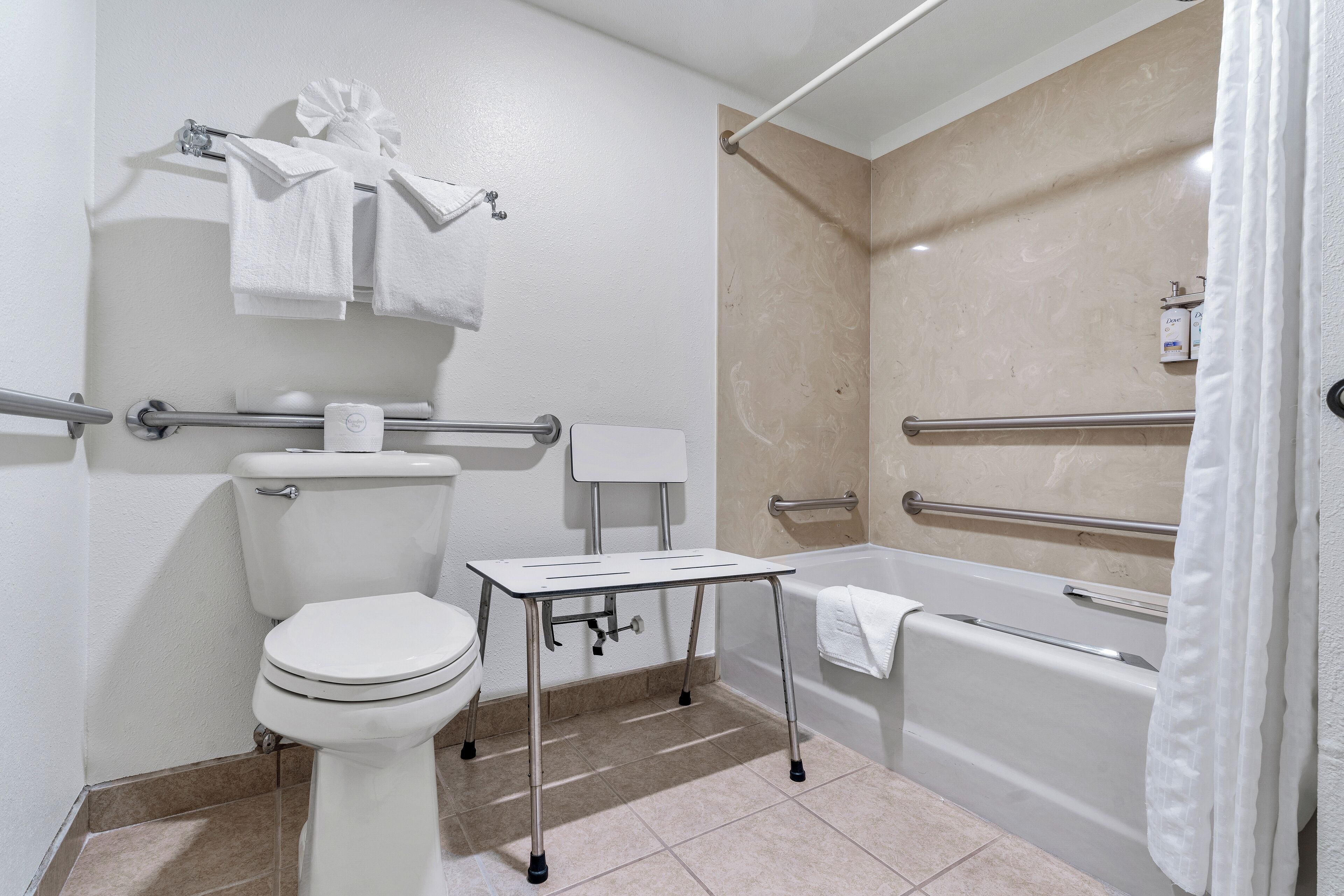 A modern bathroom with a toilet, bidet, and bathtub, equipped with grab bars and a towel rack.