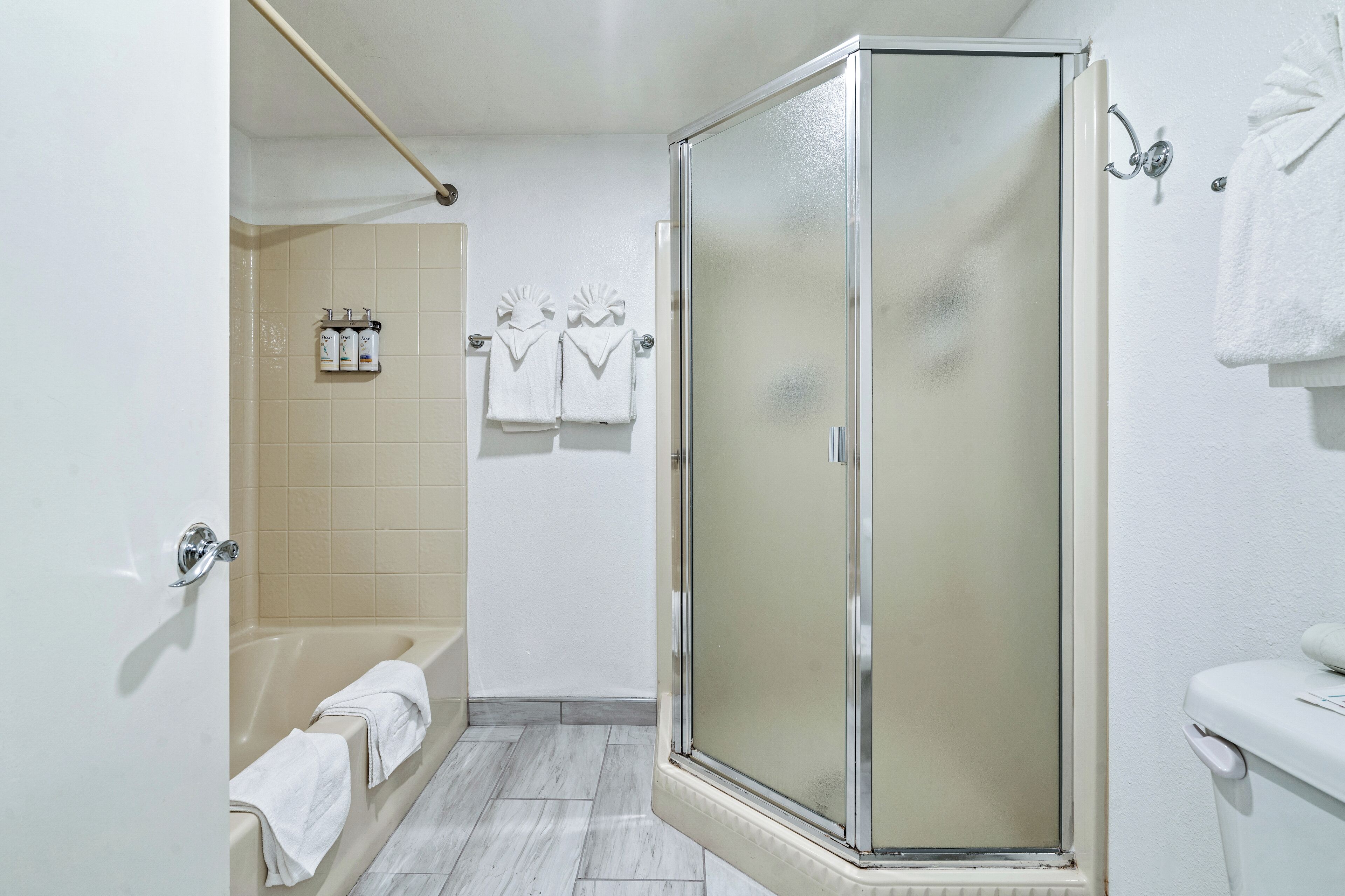 A bathroom with a glass-enclosed shower, a bathtub, and a toilet.