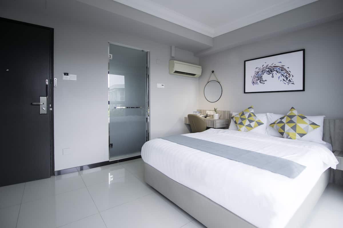 Una habitación de hotel moderna con una cama grande, una mesita de noche, un espejo y una puerta.