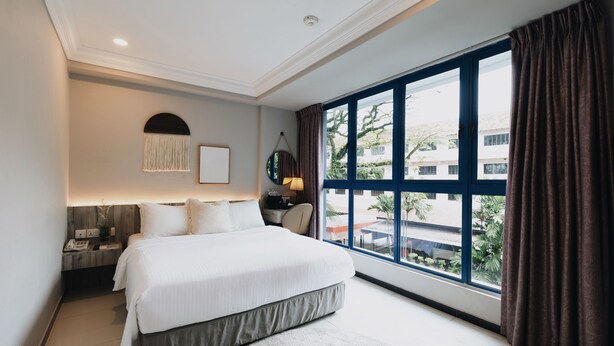 Un dormitorio moderno con una cama grande, una mesita de noche, una lámpara y vistas al exterior.