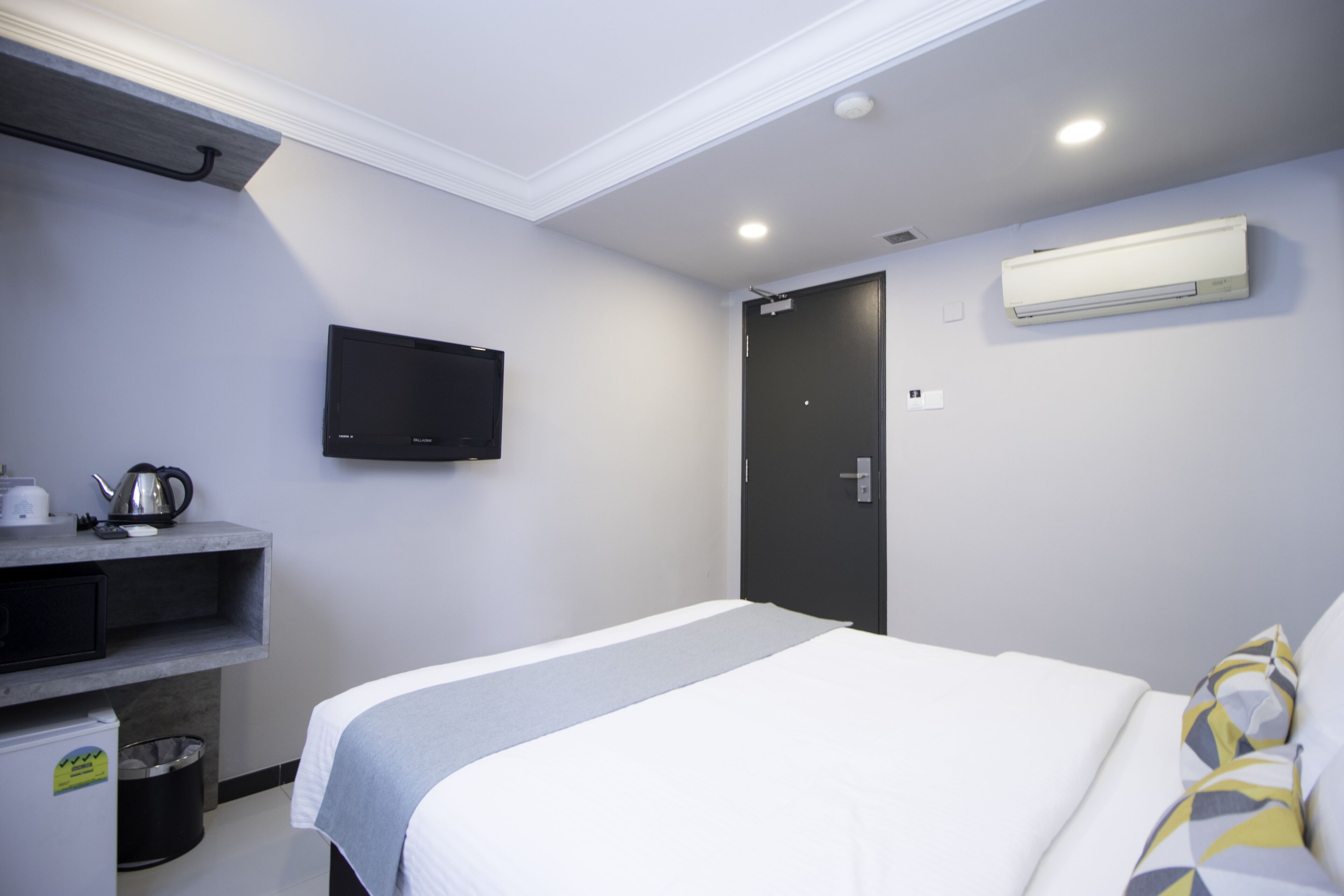 Une chambre d’hôtel équipée d’un lit, d’un téléviseur fixé au mur, d’une porte et d’un appareil de climatisation.
