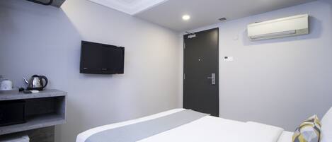 Une chambre d’hôtel équipée d’un lit, d’un téléviseur fixé au mur, d’une porte et d’un appareil de climatisation.
