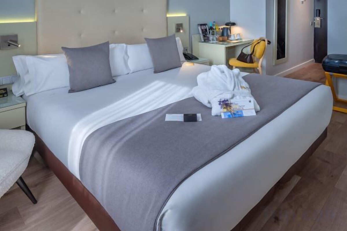 Una habitación de hotel con cama, mesita de noche y una silla.