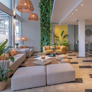 A modern lobby with a sofa set, a coffee table, and a vertical garden. - Hotel SERHS Del Port (Barcelona)