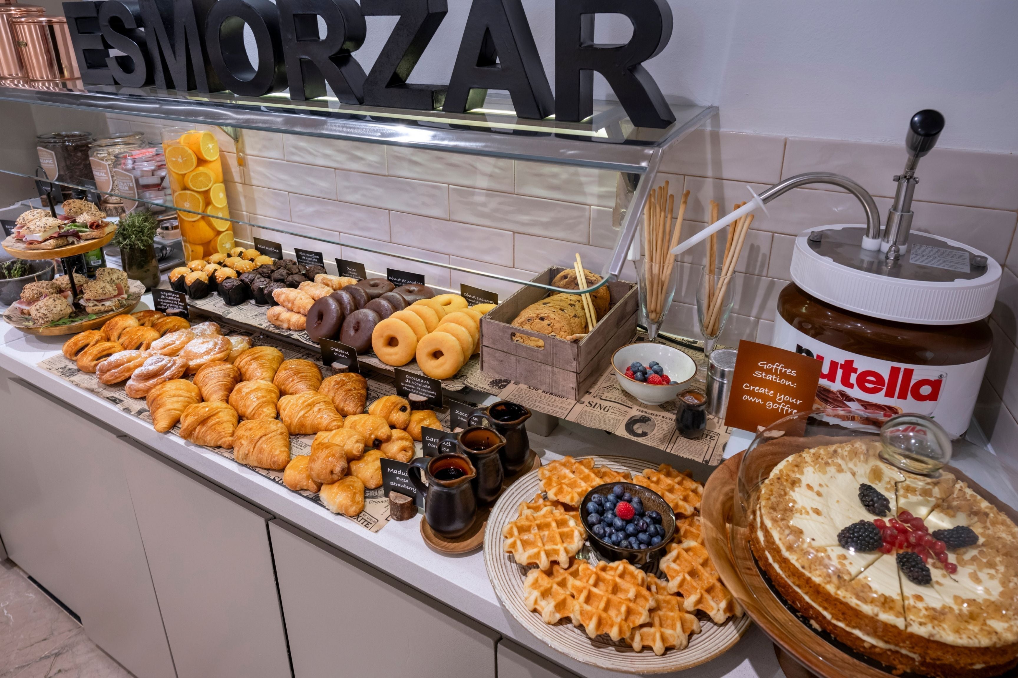 A buffet with various pastries, a Nutella jar, and a sign for a goffres station.
