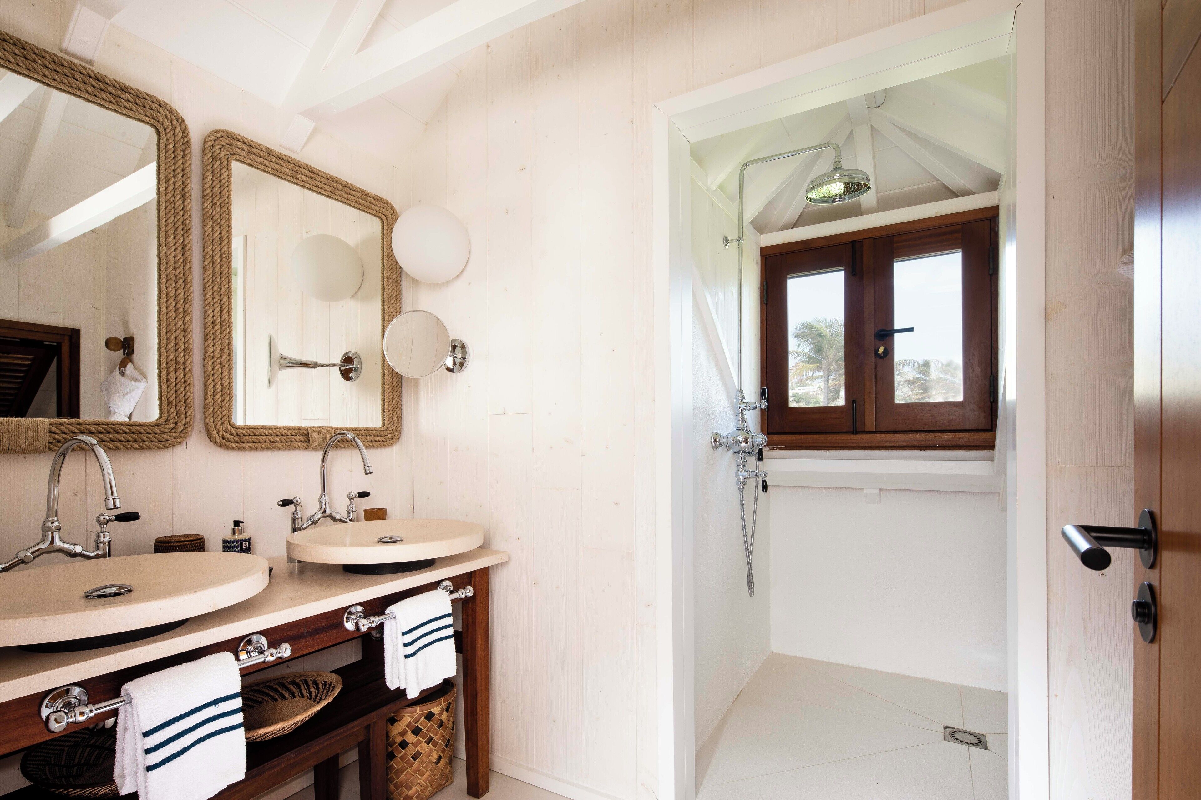 Une salle de bain avec deux lavabos, un miroir et un espace douche.