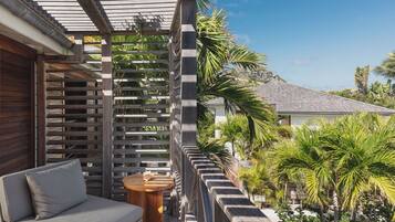 A balcony with a wooden pergola, a cushioned seating area, and a small round table.