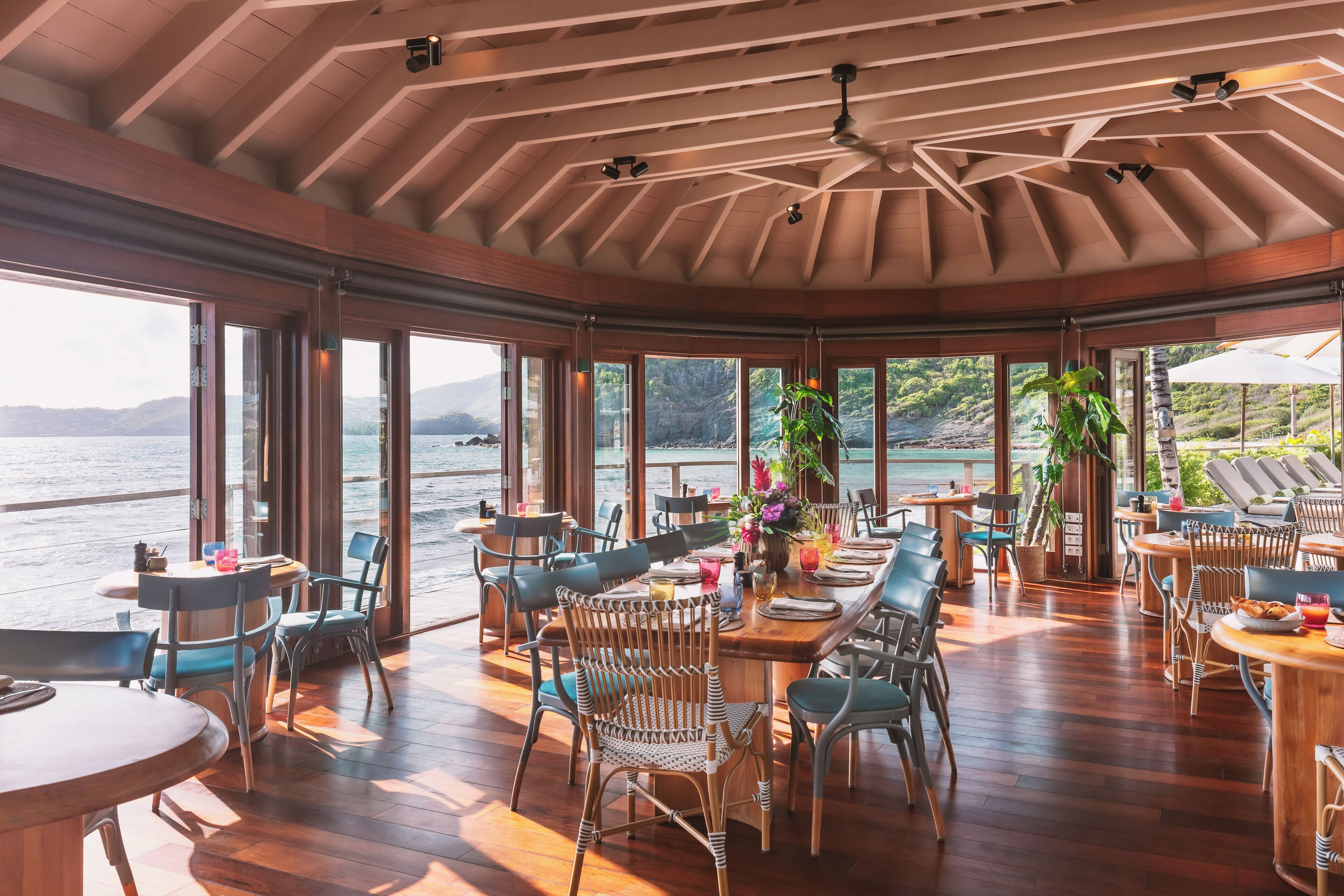 Un comedor amplio con suelo de madera y ventanas grandes con vistas a un cuerpo de agua.