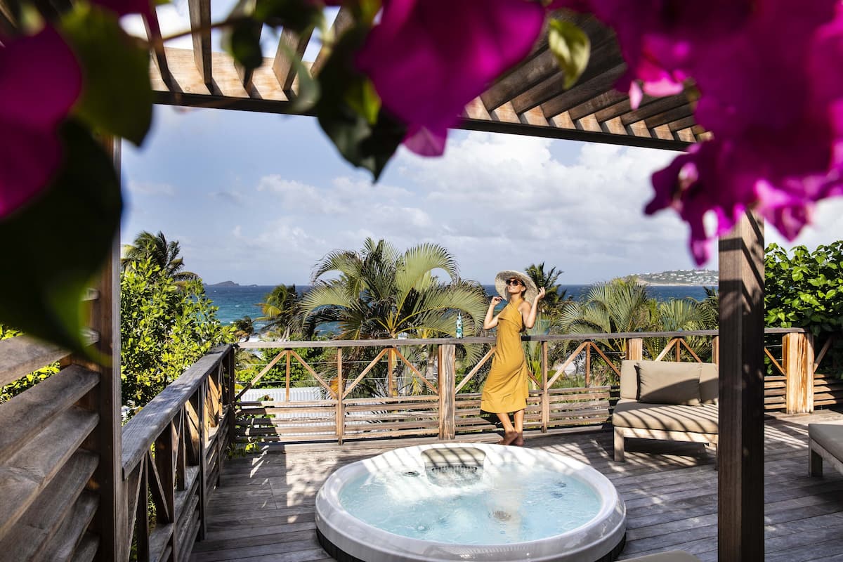 Une terrasse en bois avec un jacuzzi, une pergola en bois et une vue sur l’océan.
