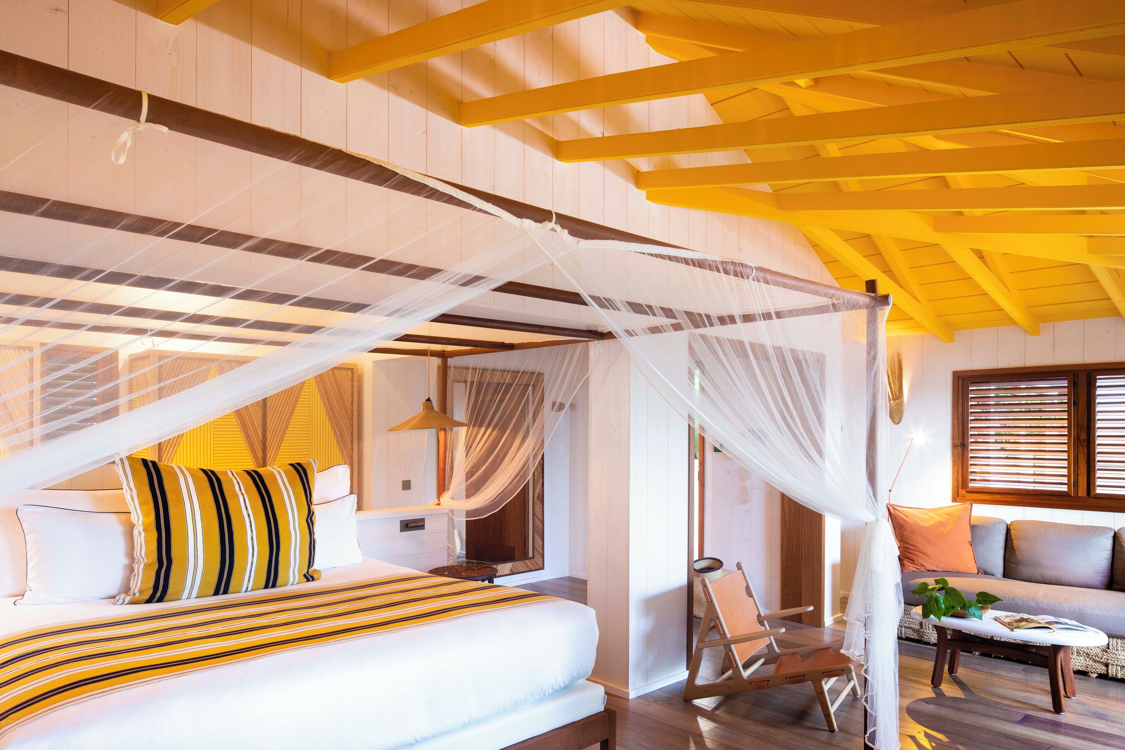 A bedroom with a bed, a chair, a sofa, and a table.
