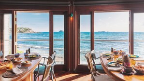 A dining area with a view of the ocean, featuring a wooden table set with plates, glasses, and cutlery. - Hotel Manapany (St. Barthelemy)