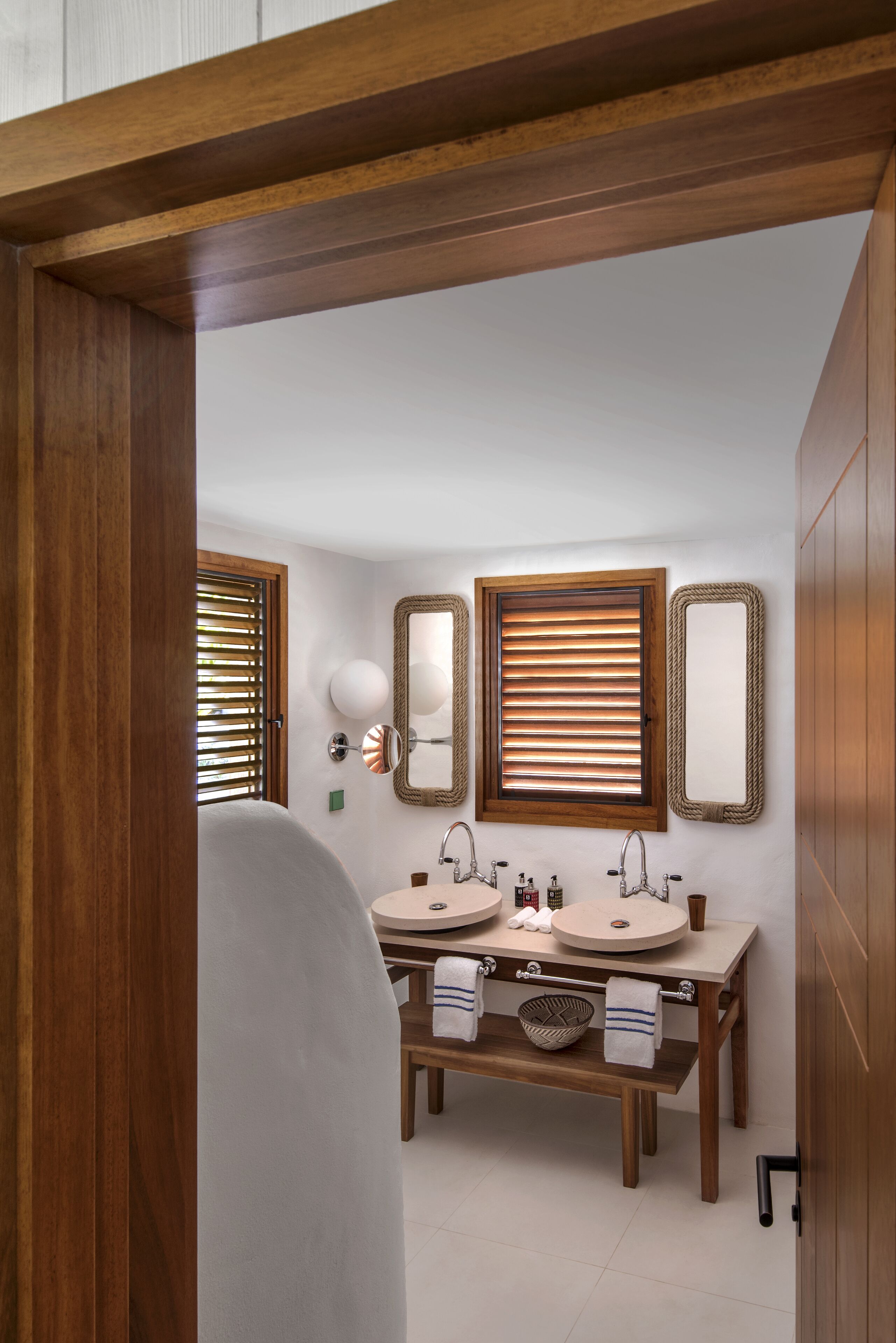 A bathroom with two sinks, wooden vanity, and three mirrors.