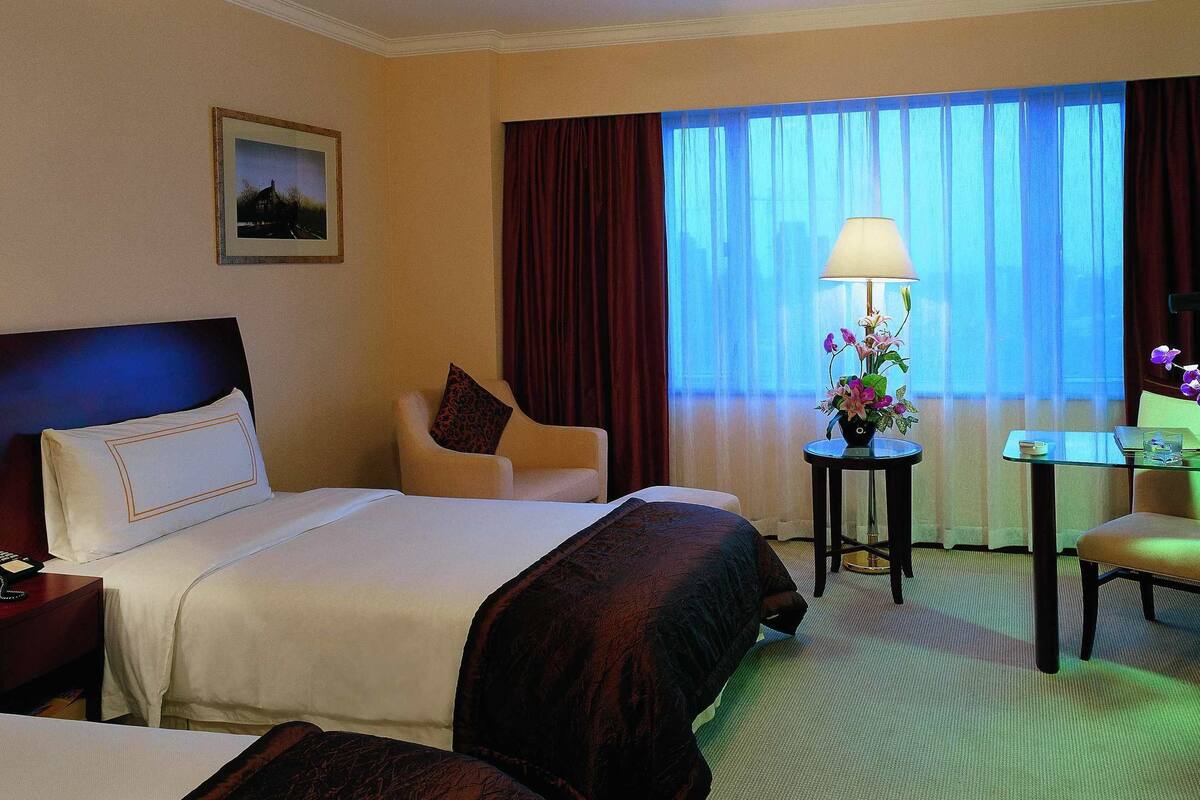 Une chambre d’hôtel équipée d’un lit, d’un bureau, d’une chaise, d’une télévision et d’une lampe.