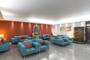Relax in a spacious lobby with comfortable seating, a central coffee table, and a large mirror.