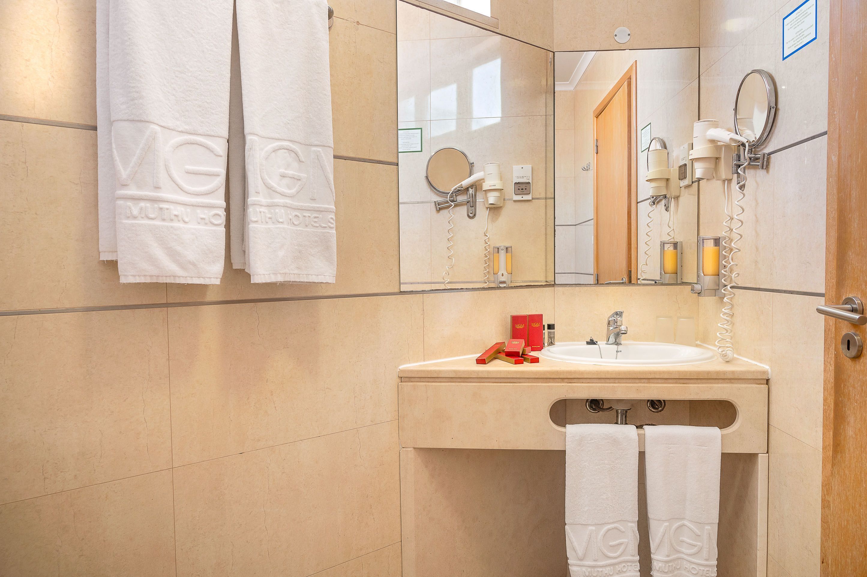 Un baño con lavamanos, espejo, toallero y artículos de aseo.