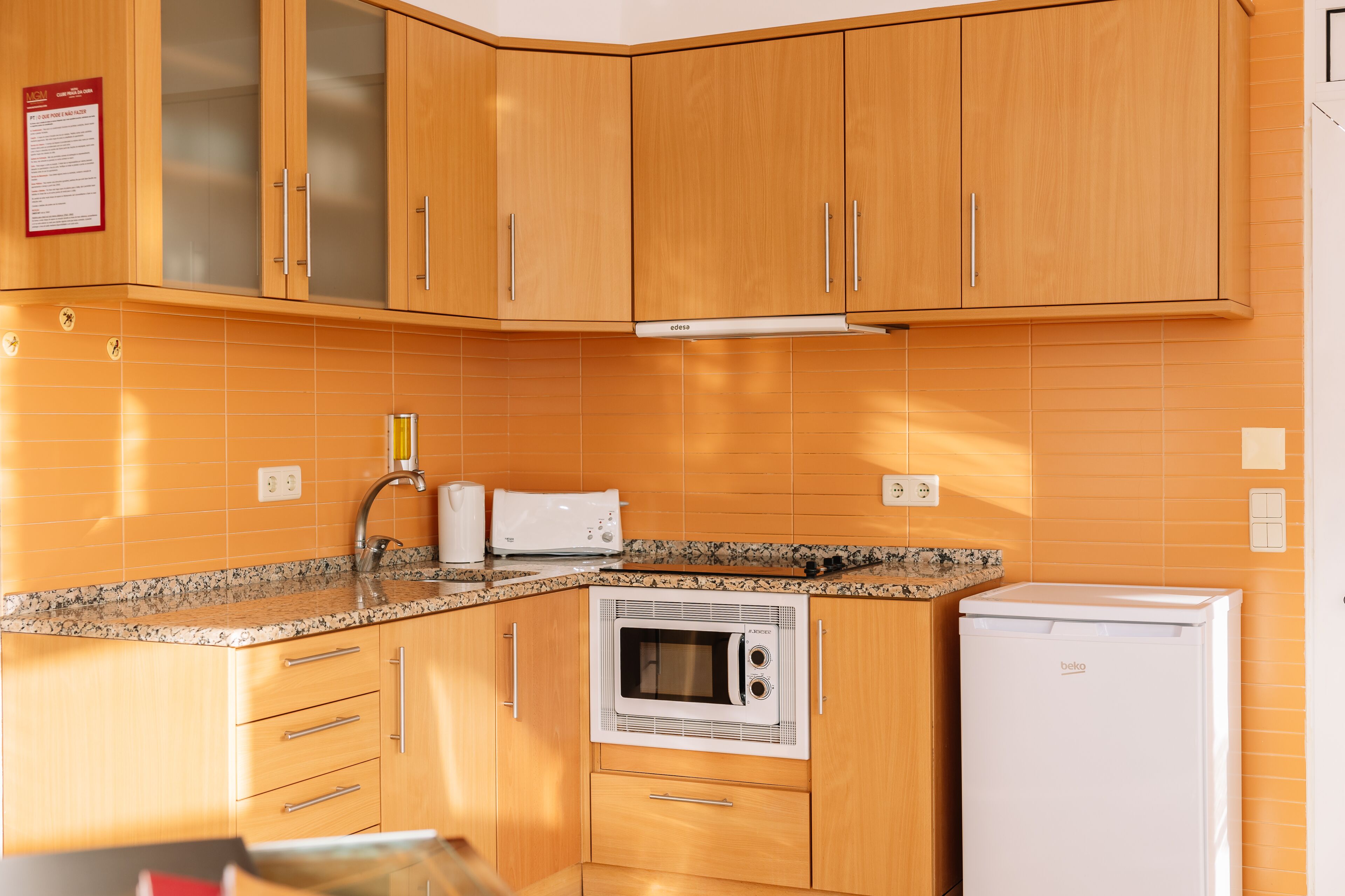Una cocina con armarios de madera, microondas integrado, tostadora y refrigerador.