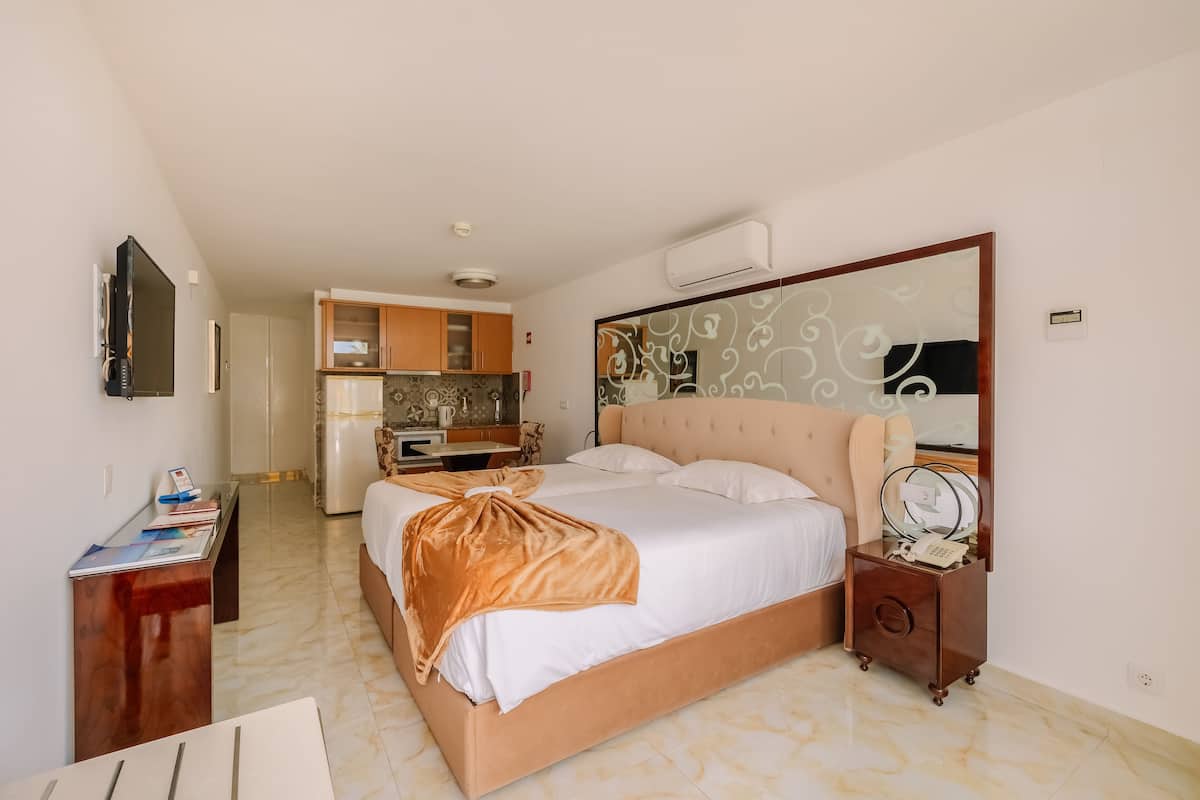 Una habitación de hotel con cama, mesita de noche y un pequeño escritorio con silla.