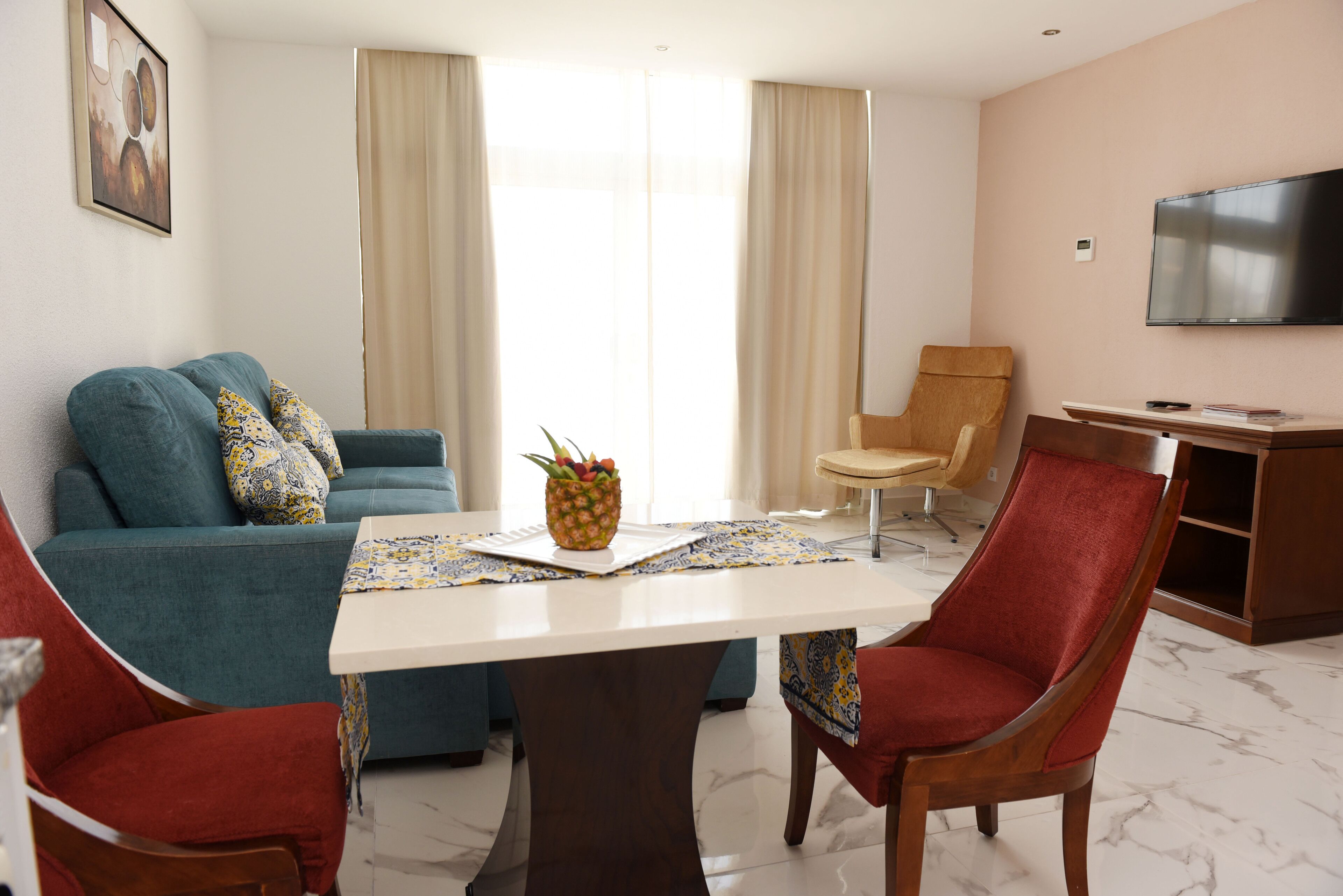 Una sala de estar con sofá, sillas, una mesa y un televisor.