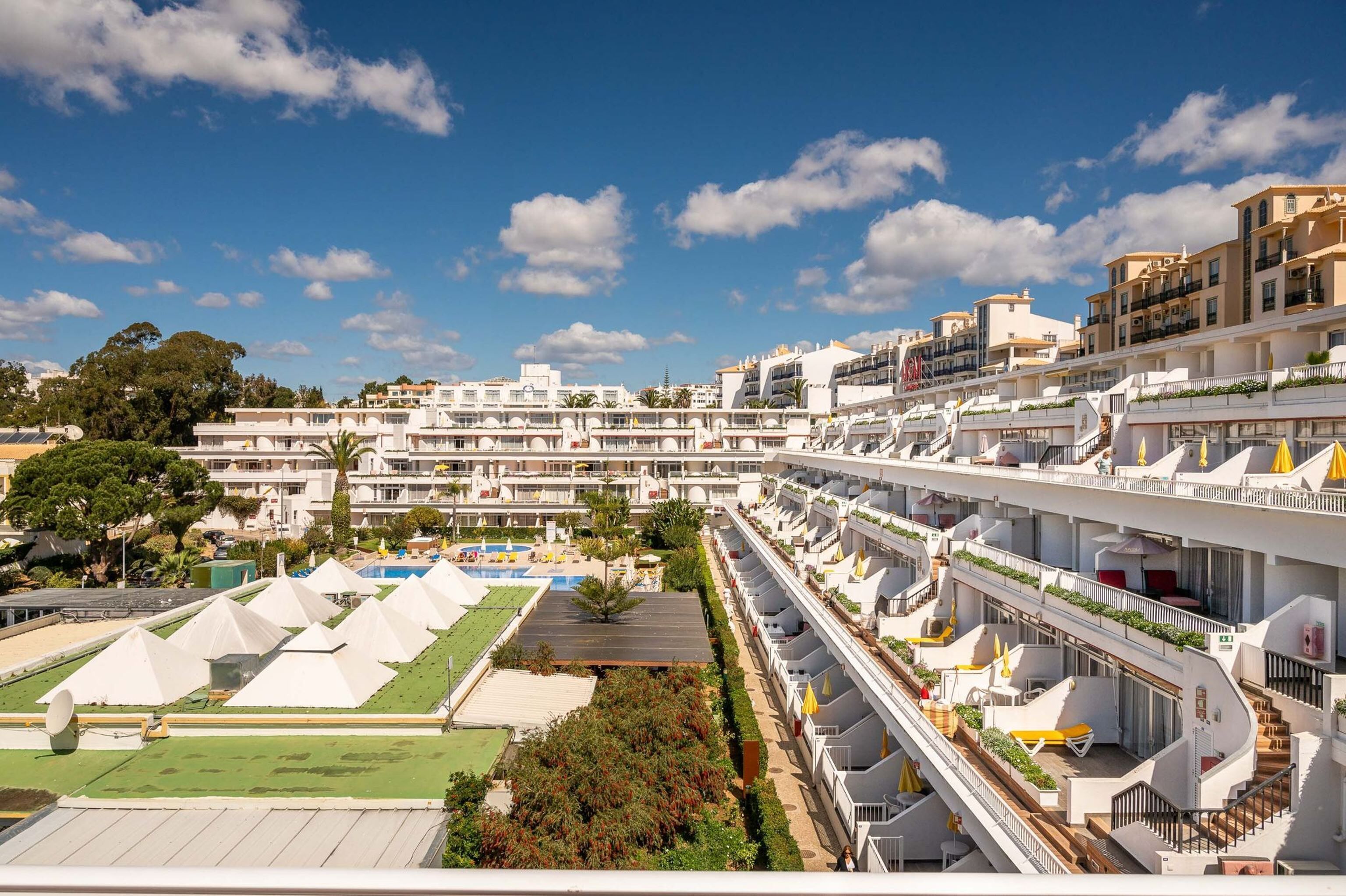 A hotel with multiple floors, balconies, and a pool area.