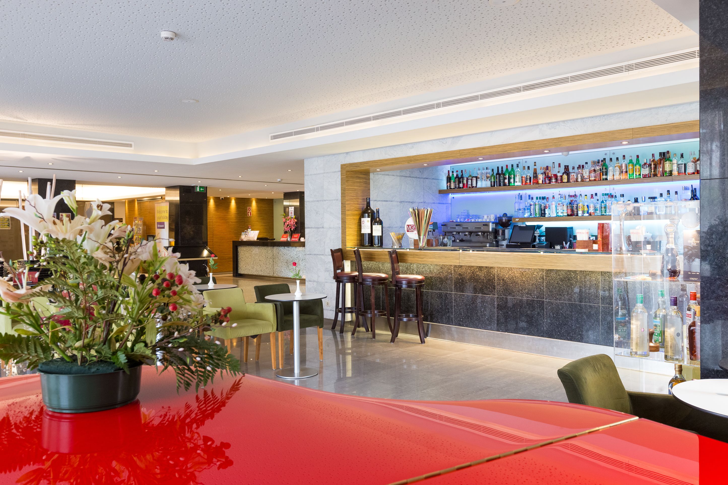 Un moderno espacio de bar con mostrador, asientos y una amplia variedad de botellas.